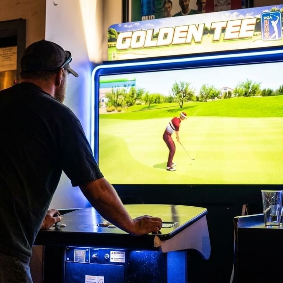 Man playing a Golden Tee golf arcade game in a dimly lit room.